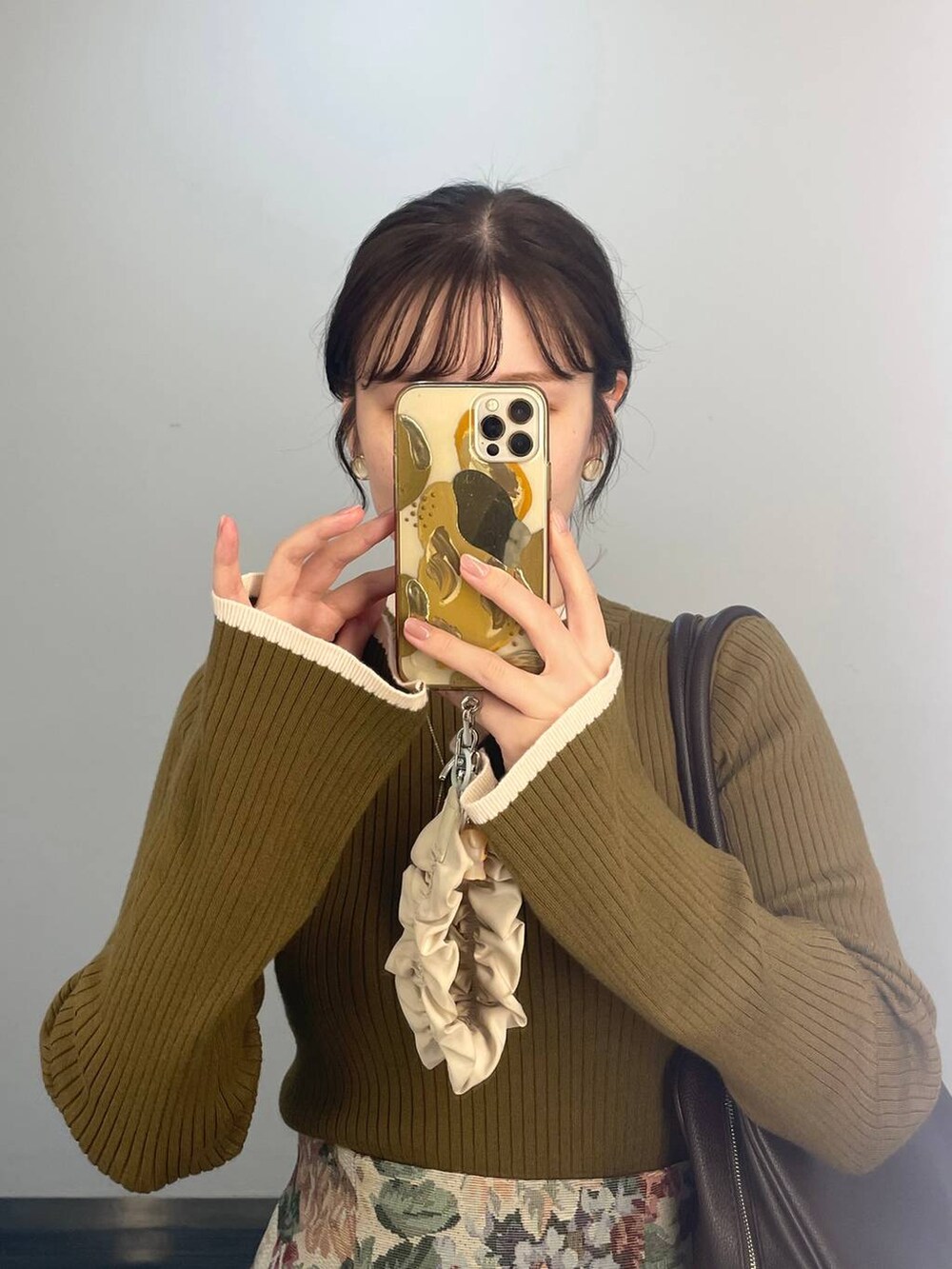 ブルー系のスカート、ブラウン系のトートバッグ、グリーン系のニット/セーターを着用したレディースの秋コーディネートの4枚目の写真