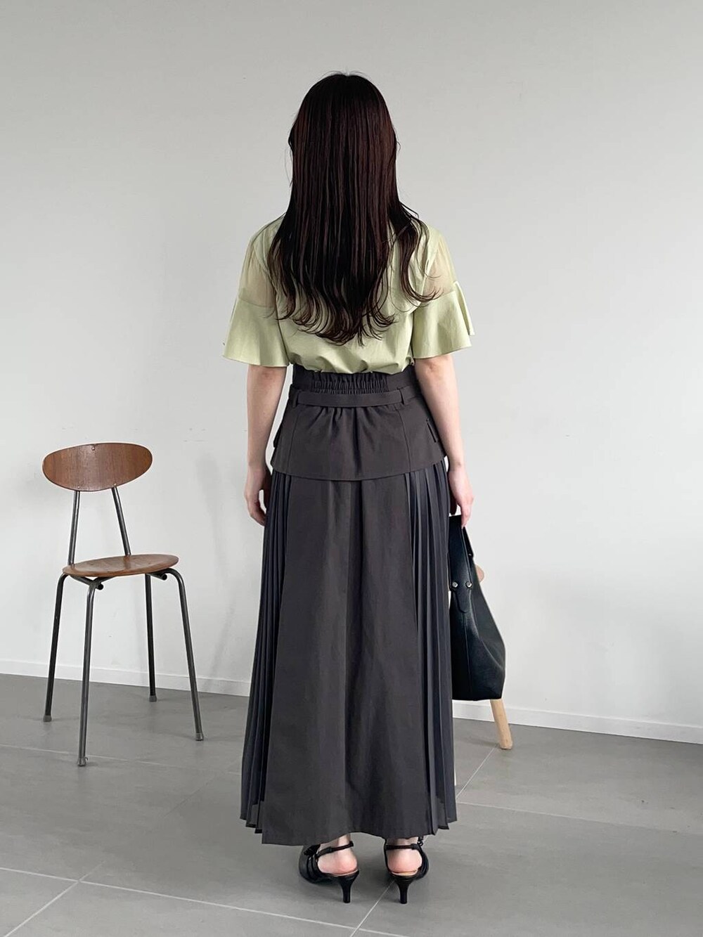 グレー系のスカート、グリーン系のTシャツ/カットソー、ブラック系のショルダーバッグを着用したレディースの春コーディネートの2枚目の写真