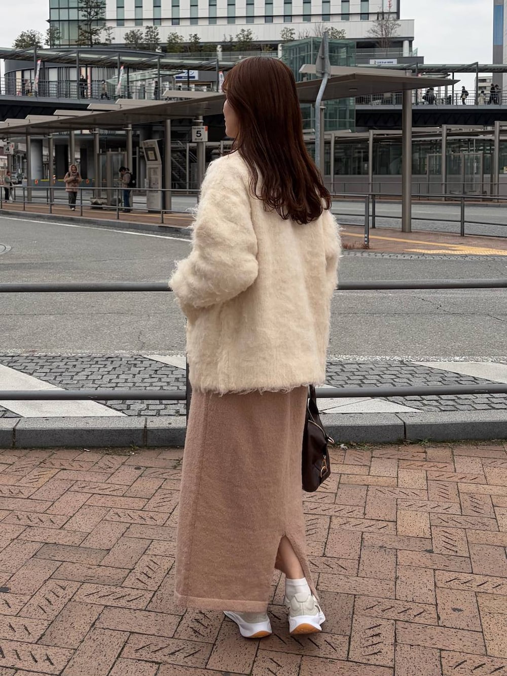 ブラウン系のボストンバッグ、ピンク系のワンピース、ホワイト系のカーディガン/ボレロを着用したレディースの冬コーディネートの2枚目の写真