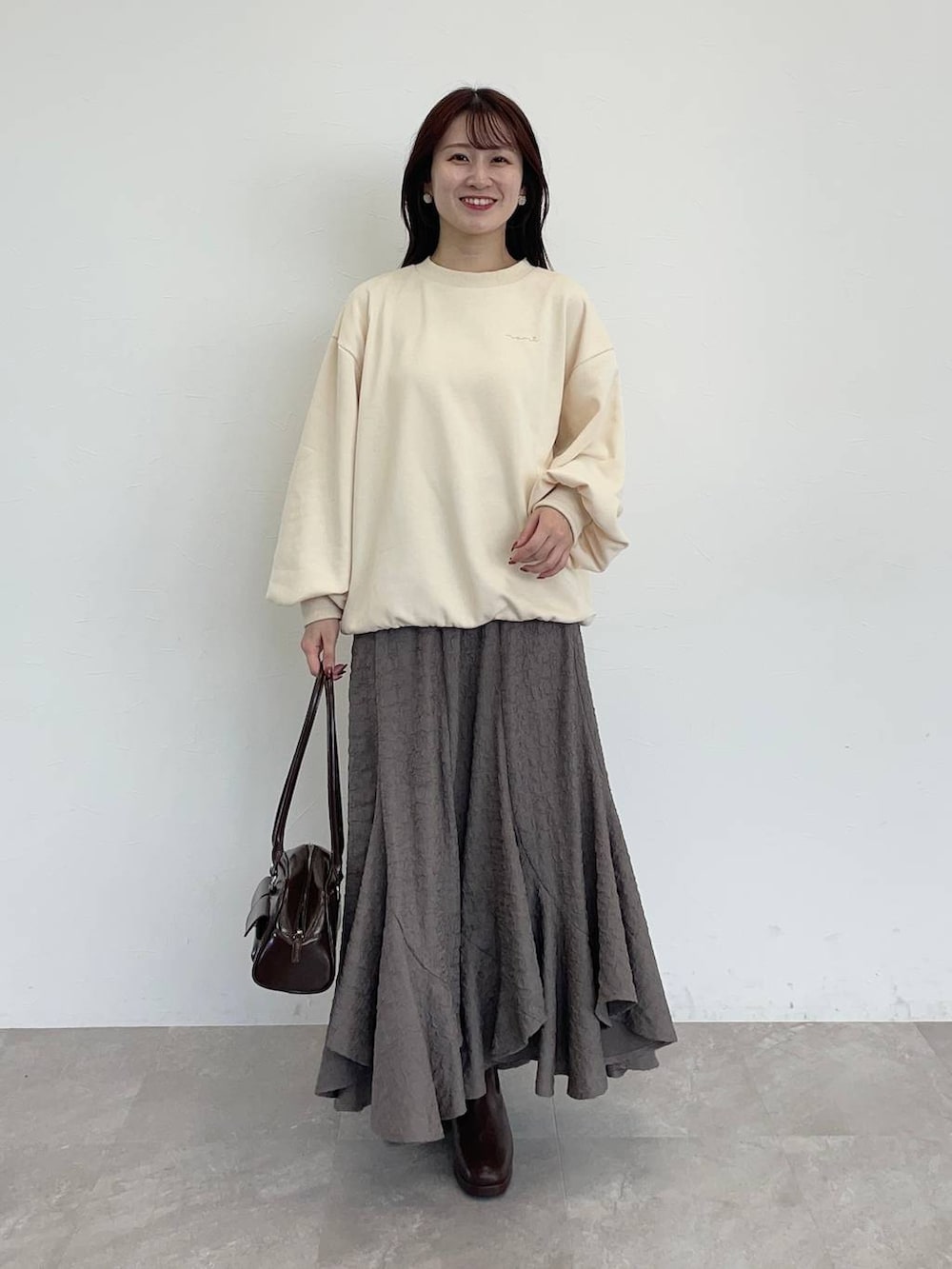 ブラウン系のブーツ、ホワイト系のスウェット、ブラウン系のスカートを着用したレディースの秋コーディネートの3枚目の写真