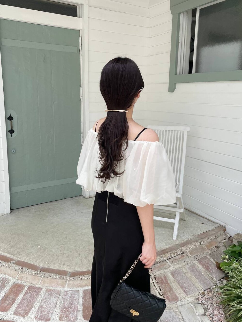 ブラック系のパンプス、ブラック系のショルダーバッグ、ブラック系のドレスを着用したレディースの夏コーディネートの5枚目の写真
