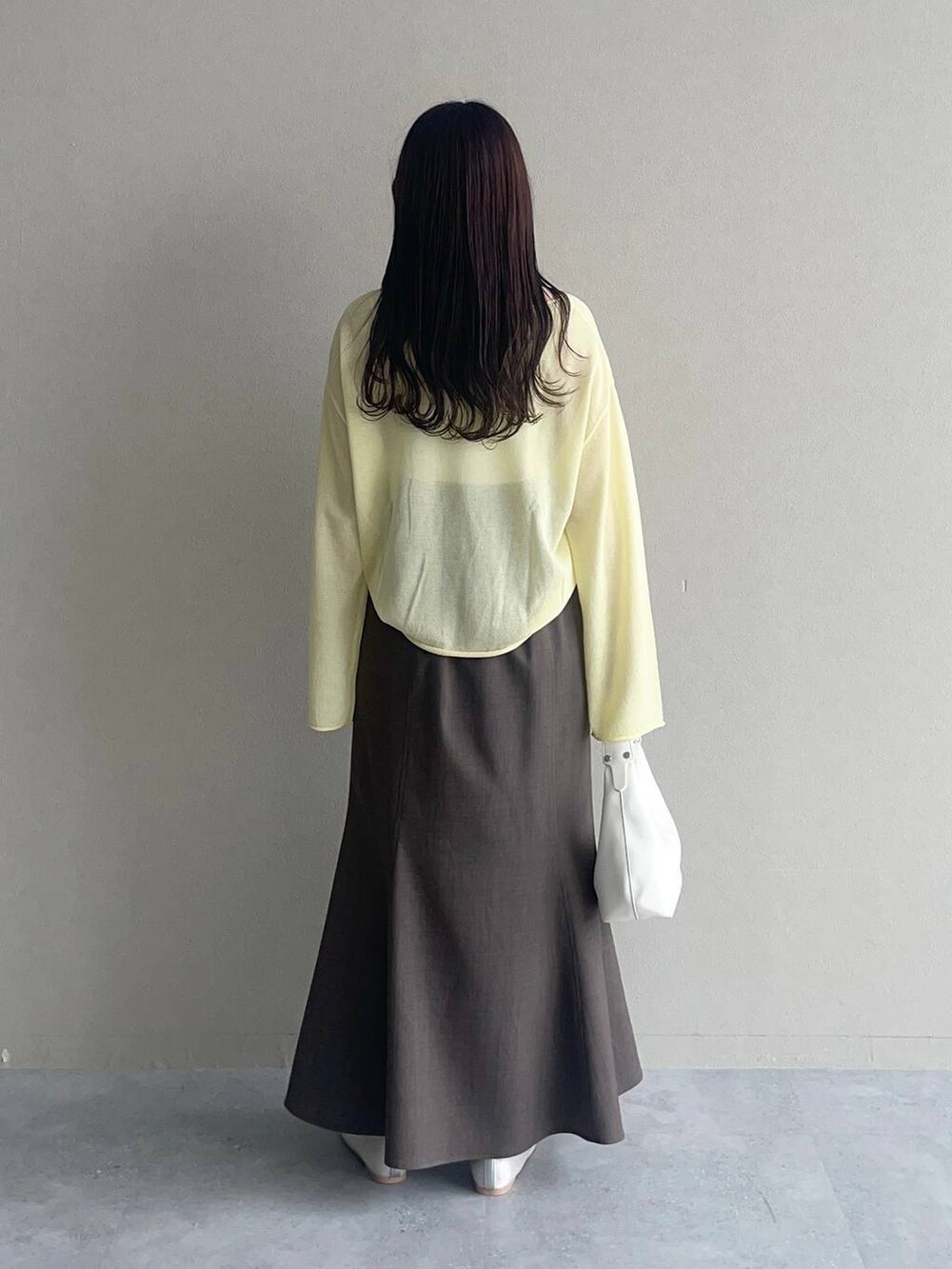 イエロー系のニット/セーター、シルバー系のバレエシューズ、グレー系のスカートを着用したレディースの春コーディネートの2枚目の写真