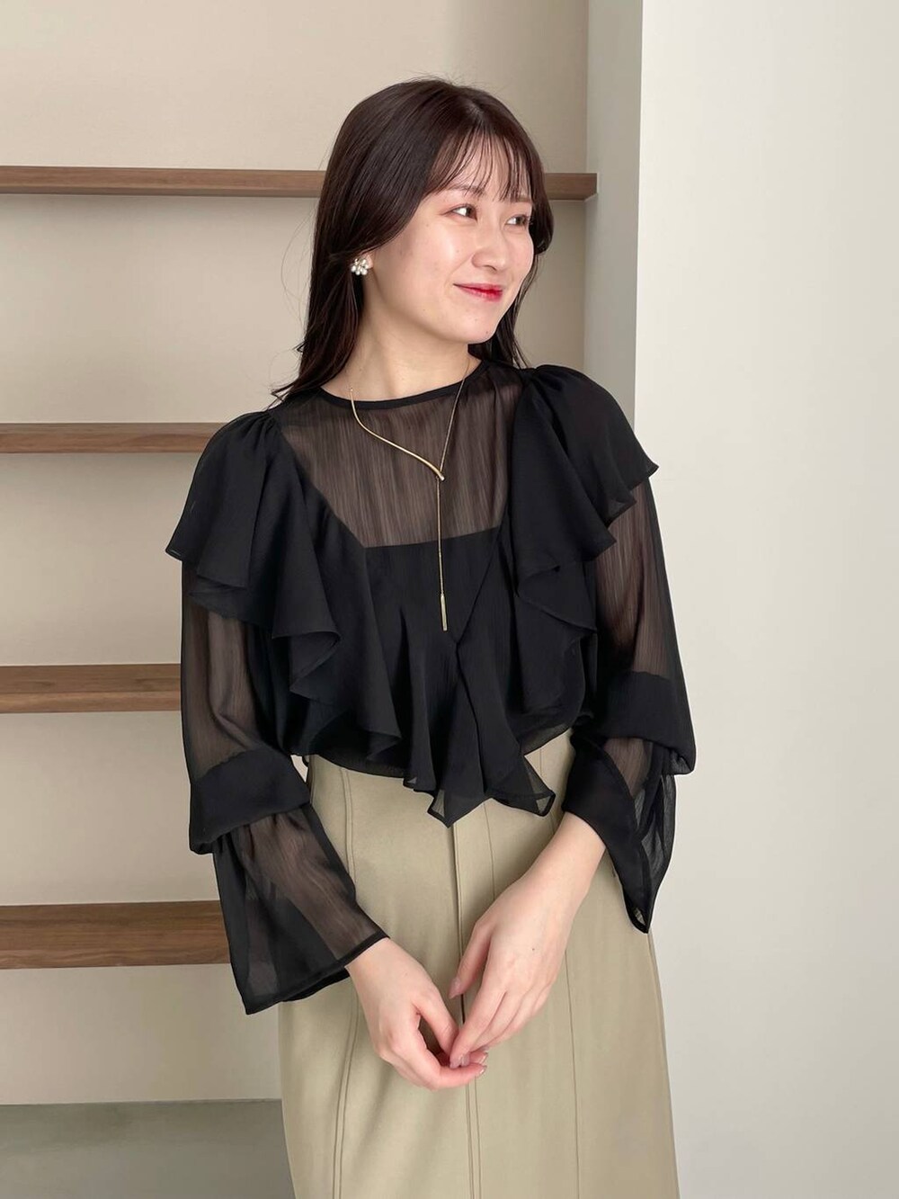 ブラック系のショルダーバッグ、ブラック系のパンプス、ベージュ系のスカートを着用したレディースの春コーディネートの3枚目の写真