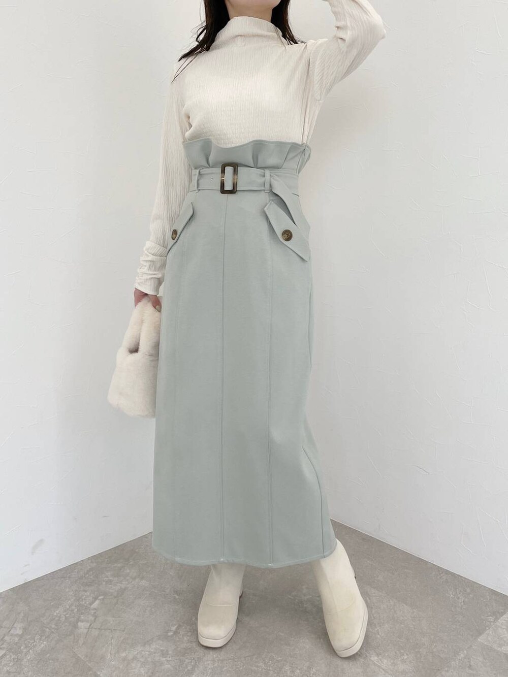 ホワイト系のブーツ、ホワイト系のハンドバッグ、グリーン系のスカートを着用したレディースの冬コーディネートの8枚目の写真