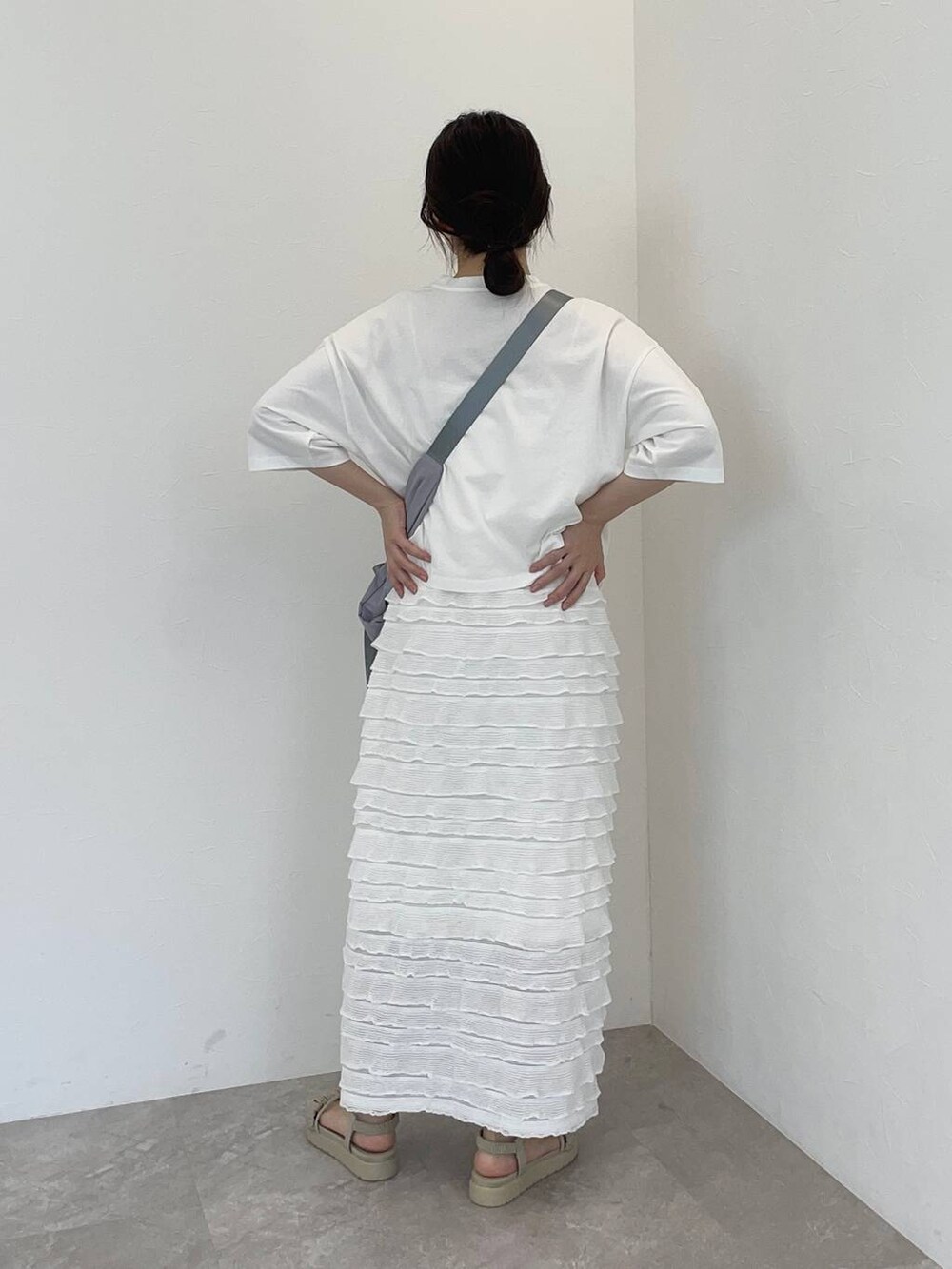 グレー系のサンダル、ホワイト系のTシャツ/カットソー、グレー系のショルダーバッグを着用したレディースの夏コーディネートの2枚目の写真