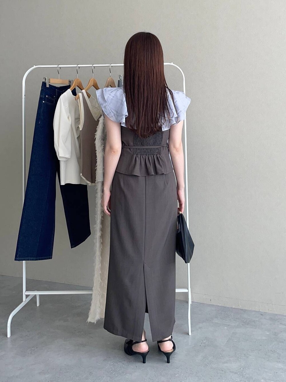 ブラック系のパンプス、ブラック系のハンドバッグ、ブルー系のシャツ/ブラウスを着用したレディースの夏コーディネートの2枚目の写真