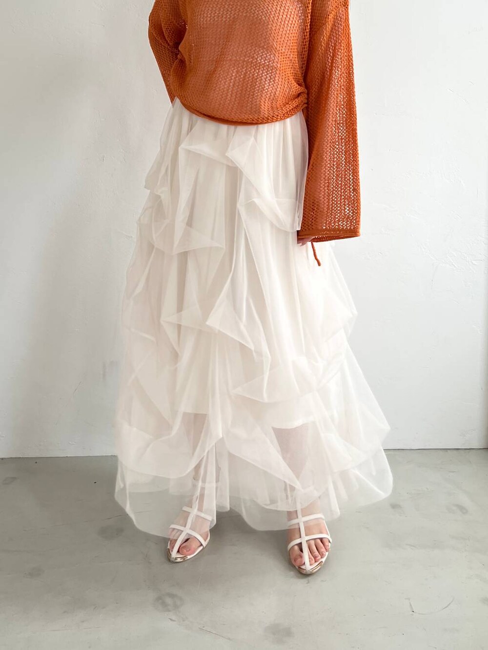 ホワイト系のスカート、オレンジ系のニット/セーター、ベージュ系のショルダーバッグを着用したレディースの夏コーディネートの4枚目の写真