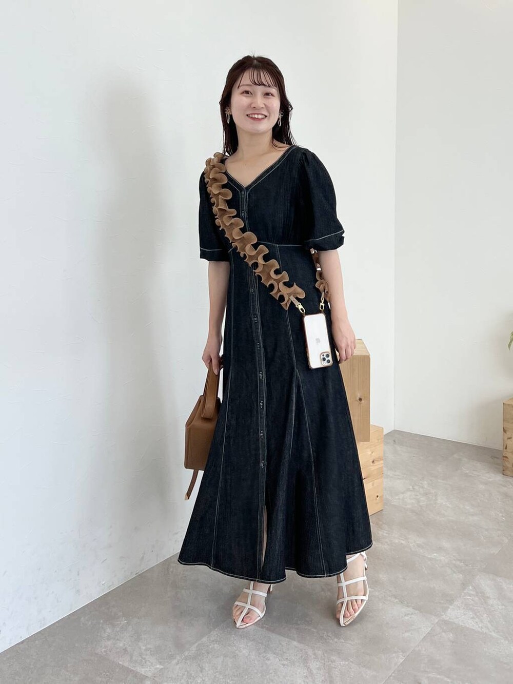 ブラウン系のショルダーバッグ、ブラック系のワンピース、ホワイト系のサンダルを着用したレディースの春コーディネートの5枚目の写真