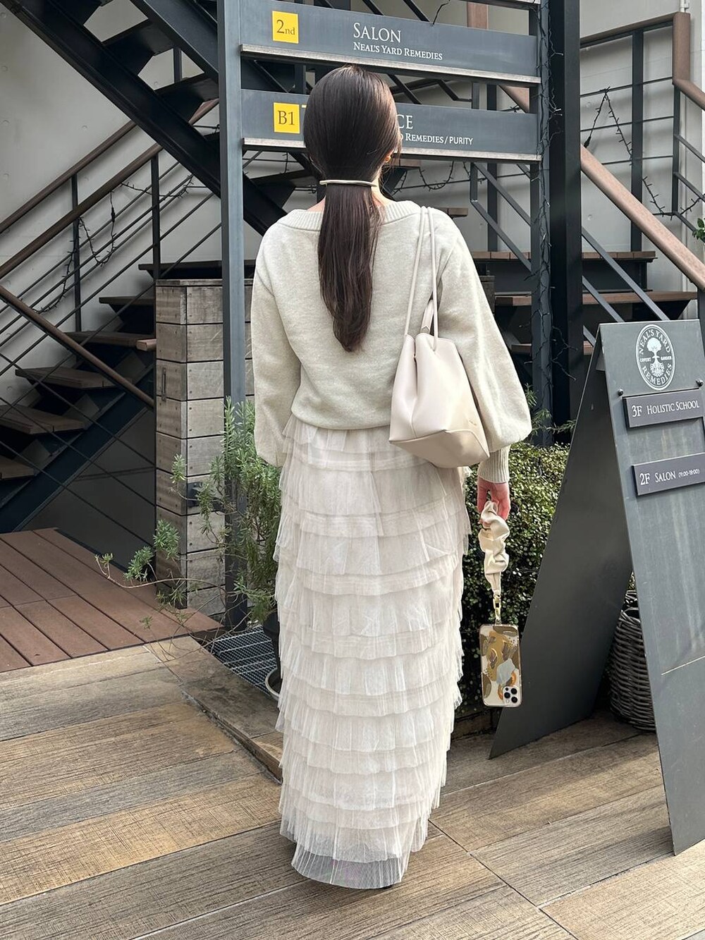 ホワイト系のスカート、ホワイト系のニット/セーター、ゴールド系のバレッタ/ヘアクリップを着用したレディースの冬コーディネートの2枚目の写真