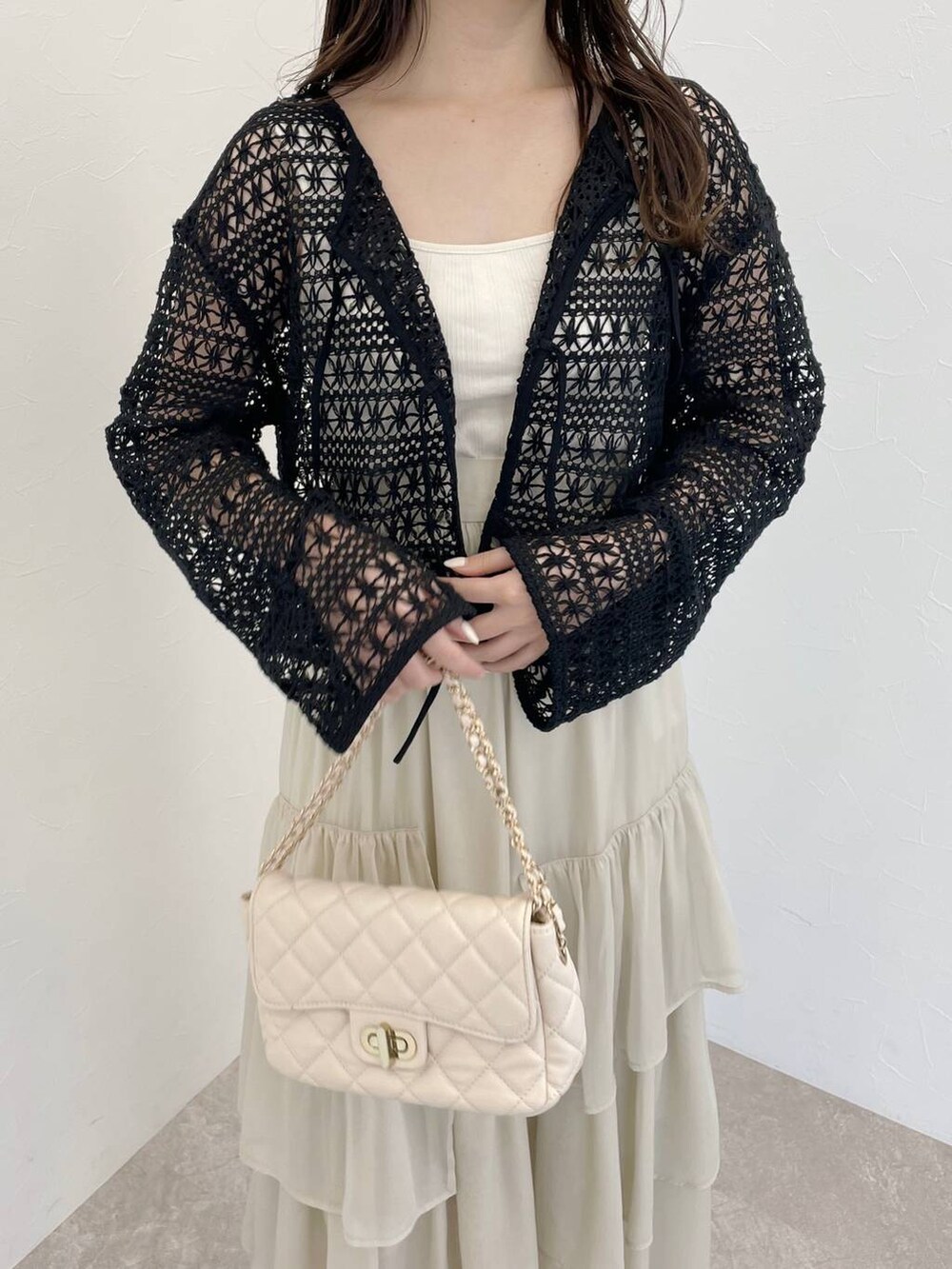 ホワイト系のスカート、ブラック系のカーディガン/ボレロ、ホワイト系のショルダーバッグを着用したレディースの春コーディネートの3枚目の写真