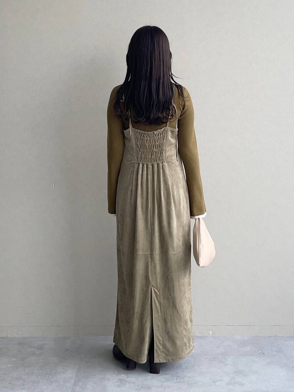 ベージュ系のハンドバッグ、ベージュ系のワンピース、ブラウン系のブーツを着用したレディースの秋コーディネートの2枚目の写真