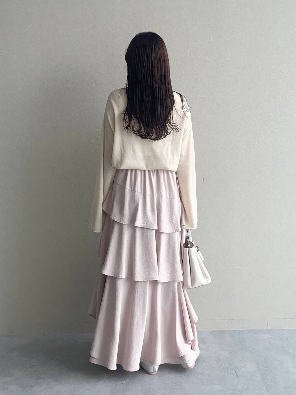 ピンク系のスカート、ホワイト系のニット/セーター、ホワイト系のショルダーバッグを着用したレディースの春コーディネートの2枚目の写真