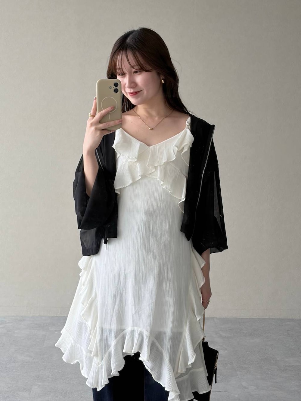 ブラック系のパーカー、ブラウン系のサンダル、ブルー系のデニムパンツを着用したレディースの春コーディネートの2枚目の写真