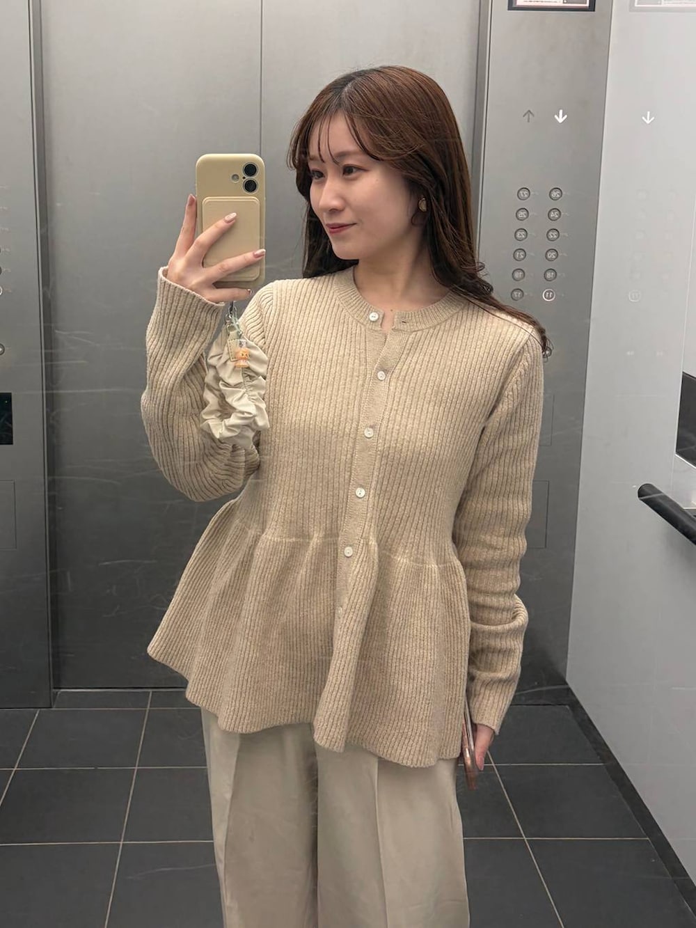 ブラウン系のボストンバッグ、ホワイト系のスラックス、ベージュ系のカーディガン/ボレロを着用したレディースの冬コーディネートの3枚目の写真