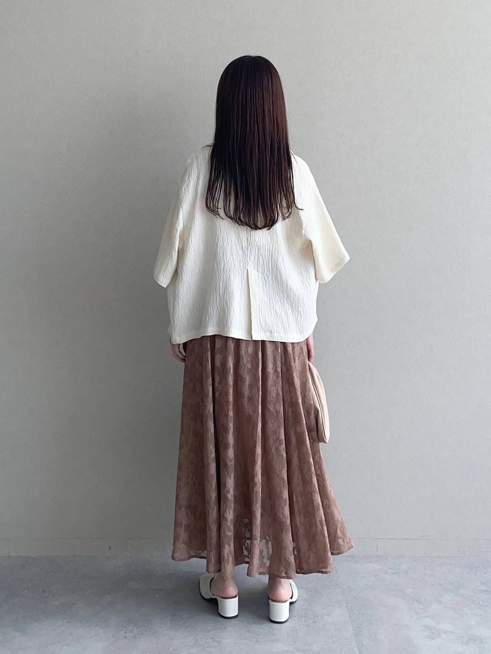 ホワイト系のテーラードジャケット、ベージュ系のハンドバッグ、ホワイト系のタンクトップを着用したレディースの秋コーディネートの2枚目の写真