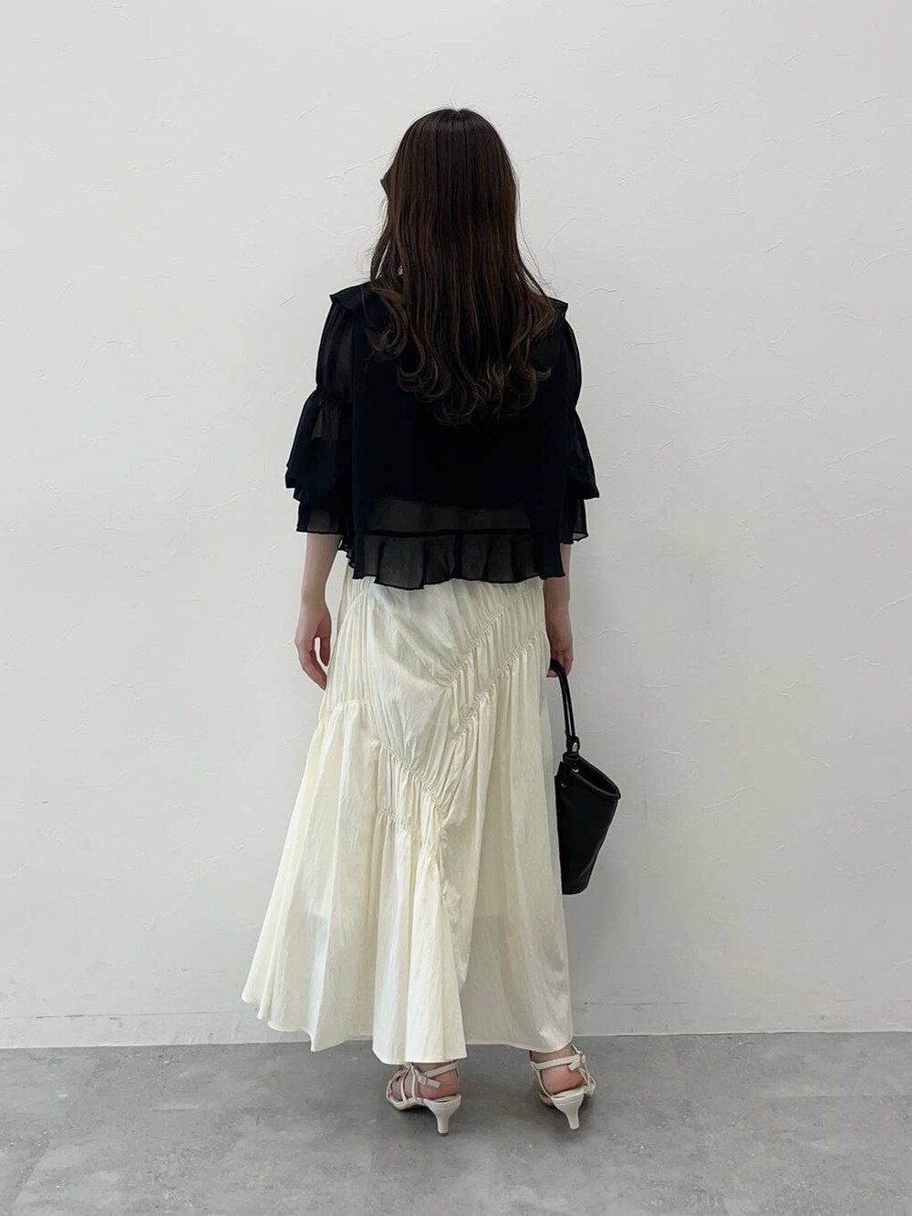 ブラック系のシャツ/ブラウス、ブラック系のハンドバッグ、ホワイト系のサンダルを着用したレディースの春コーディネートの2枚目の写真