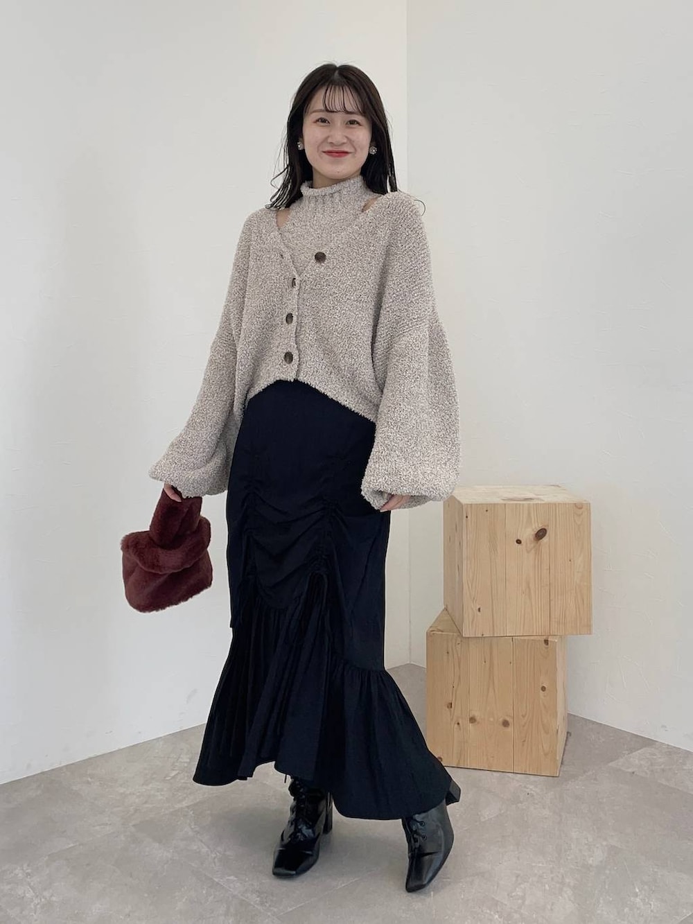 ブラック系のブーツ、ピンク系のハンドバッグ、ブラック系のスカートを着用したレディースの秋コーディネートの2枚目の写真