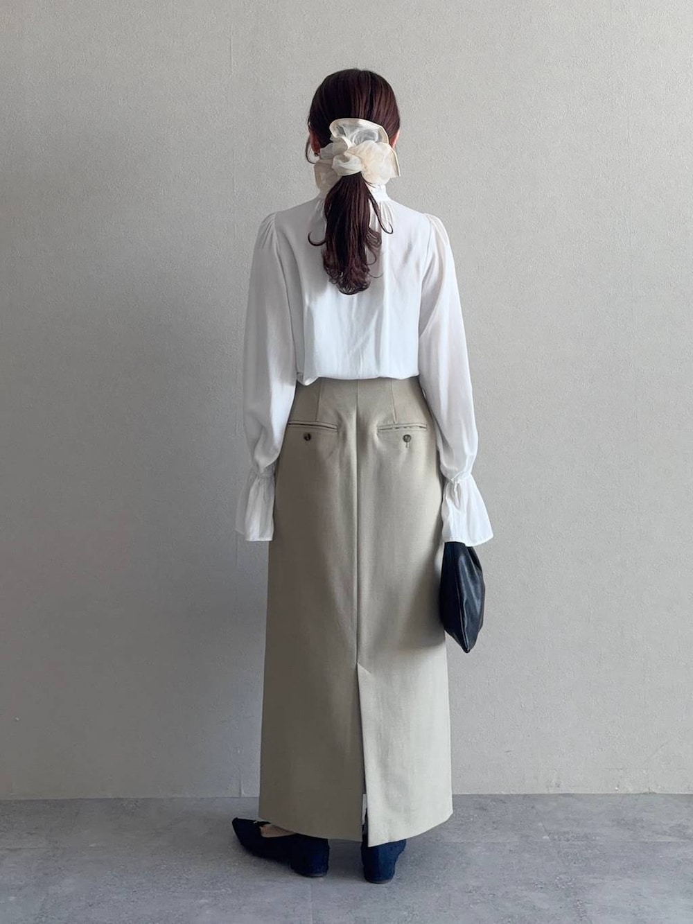 ブラック系のハンドバッグ、ベージュ系のテーラードジャケット、ベージュ系のスカートを着用したレディースの冬コーディネートの4枚目の写真