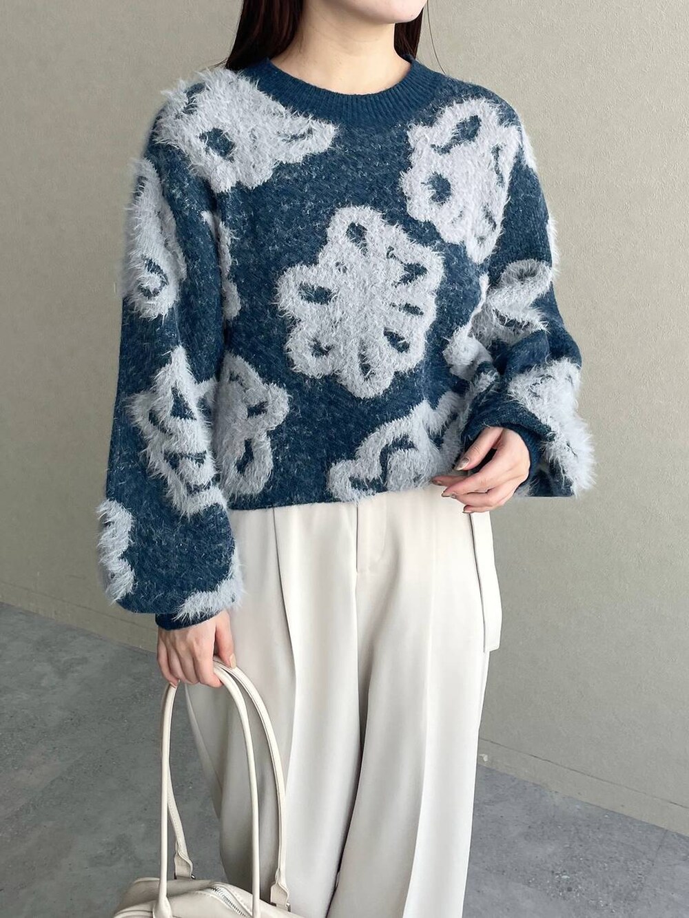 ブルー系のニット/セーター、ホワイト系のブーツ、ホワイト系のハンドバッグを着用したレディースの冬コーディネートの3枚目の写真