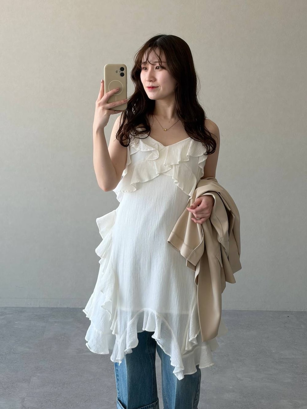 ブラック系のサンダル、ベージュ系のテーラードジャケット、ブルー系のデニムパンツを着用したレディースの春コーディネートの4枚目の写真