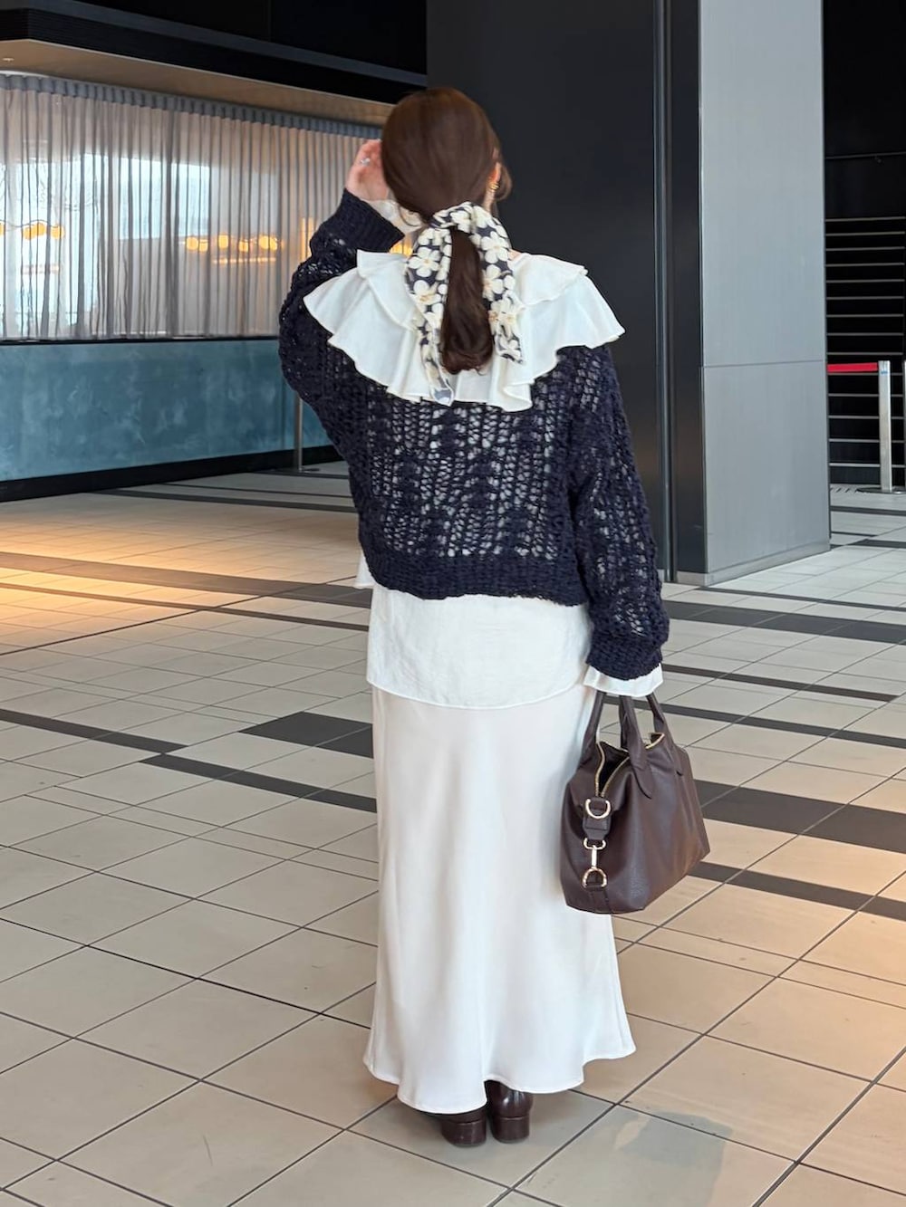 ブラウン系のボストンバッグ、ホワイト系のシャツ/ブラウス、ブルー系のニット/セーターを着用したレディースの冬コーディネートの2枚目の写真