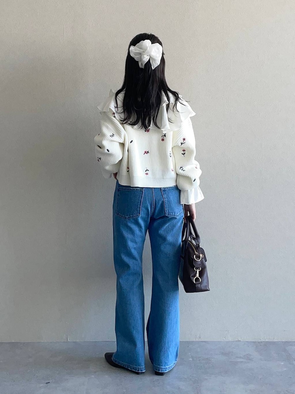 ブラウン系のボストンバッグ、ブルー系のデニムパンツ、ホワイト系のシャツ/ブラウスを着用したレディースの冬コーディネートの2枚目の写真