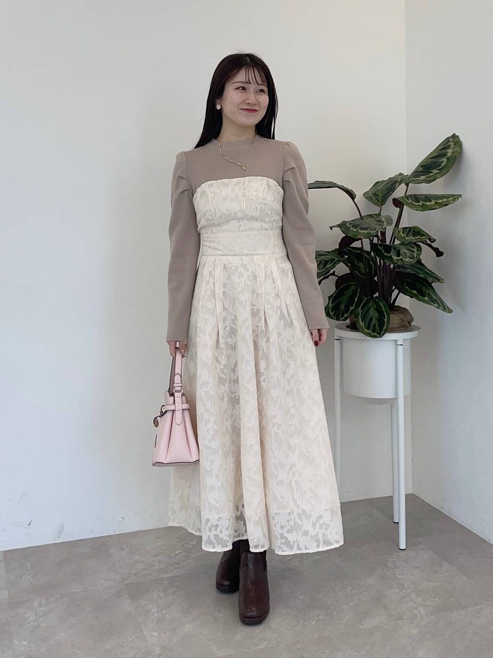 ホワイト系のチェスターコート、ピンク系のショルダーバッグ、ブラウン系のブーツを着用したレディースの冬コーディネートの3枚目の写真