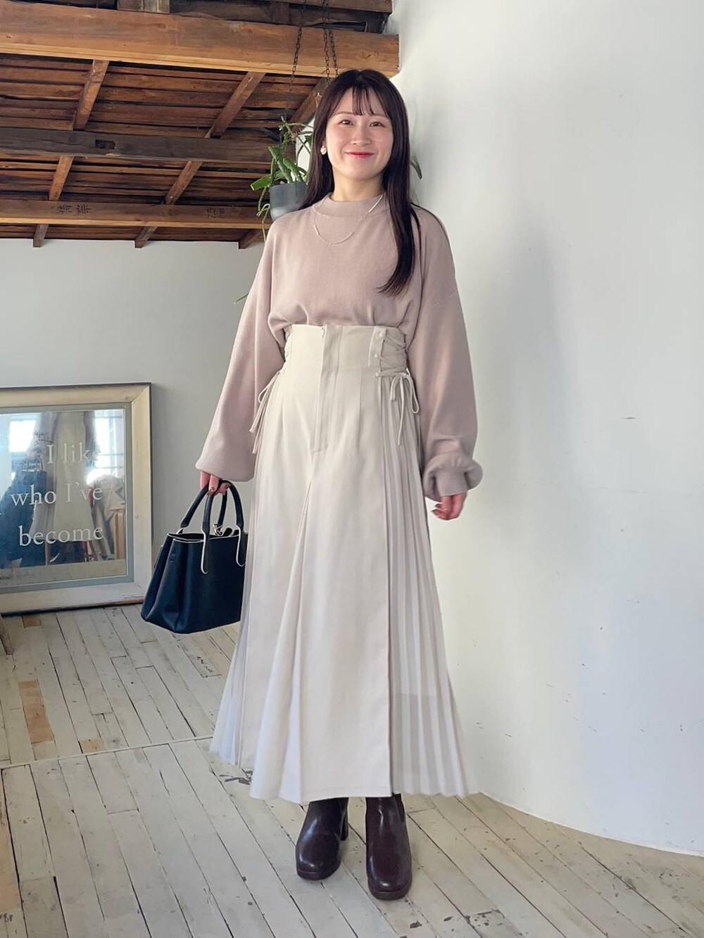 グレー系のピーコート、ブラウン系のブーツ、ホワイト系のスカートを着用したレディースの冬コーディネートの3枚目の写真