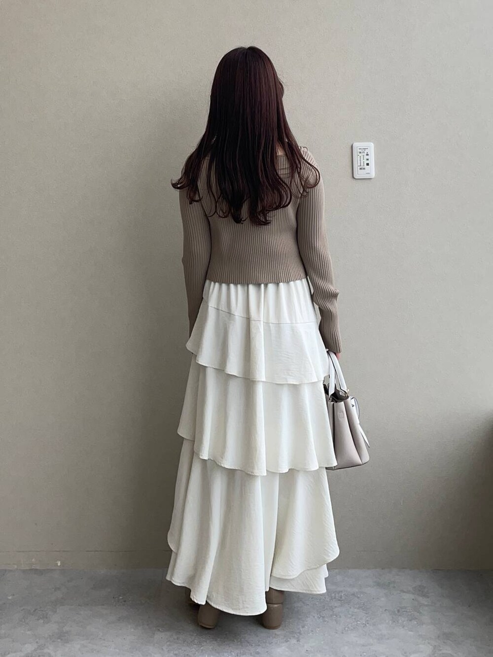 ホワイト系のスカート、ベージュ系のショルダーバッグ、ブラウン系のパンプスを着用したレディースの冬コーディネートの2枚目の写真