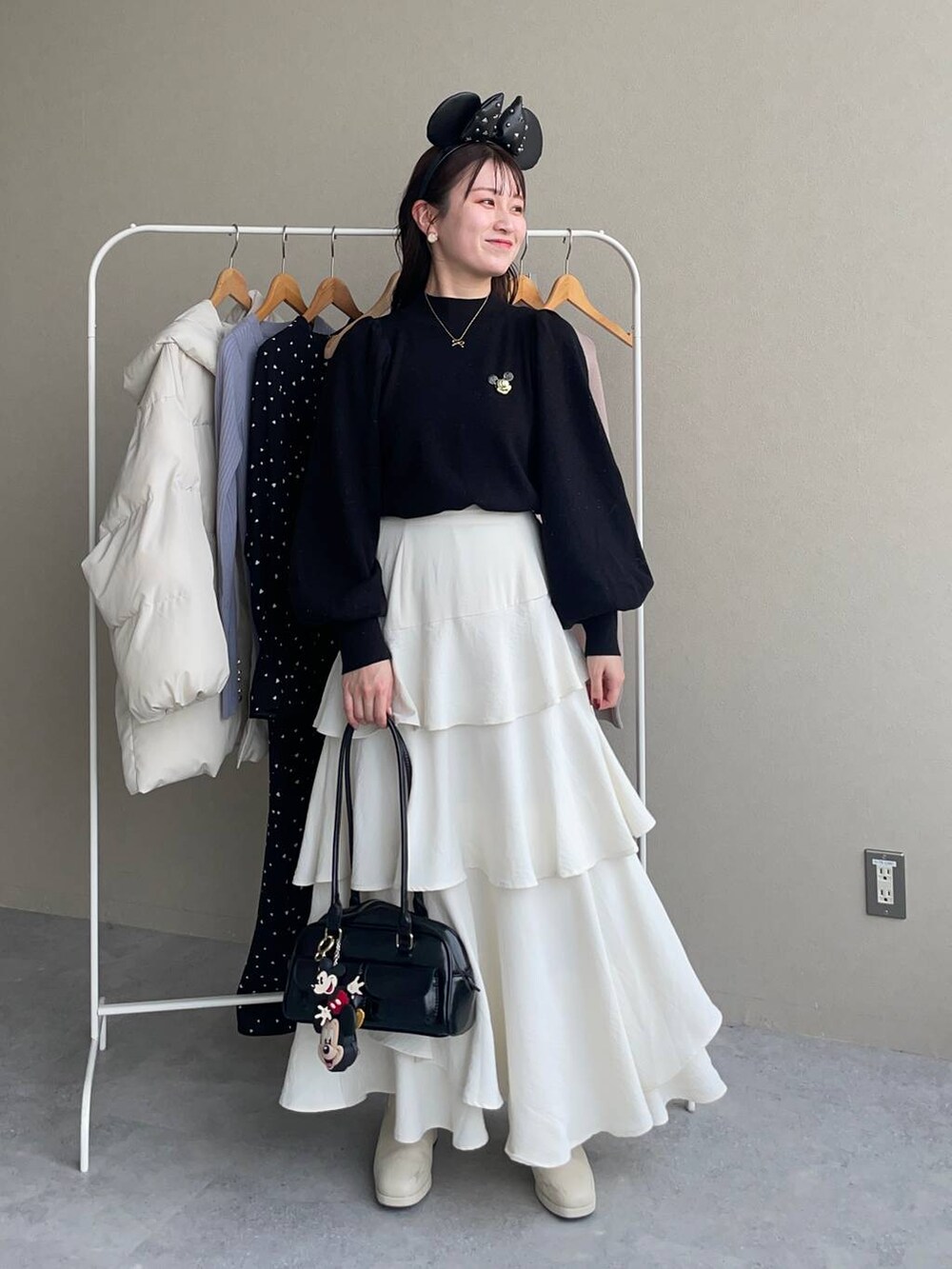 ホワイト系のブーツ、ホワイト系のスカート、ブラック系のハンドバッグを着用したレディースの秋コーディネートの3枚目の写真