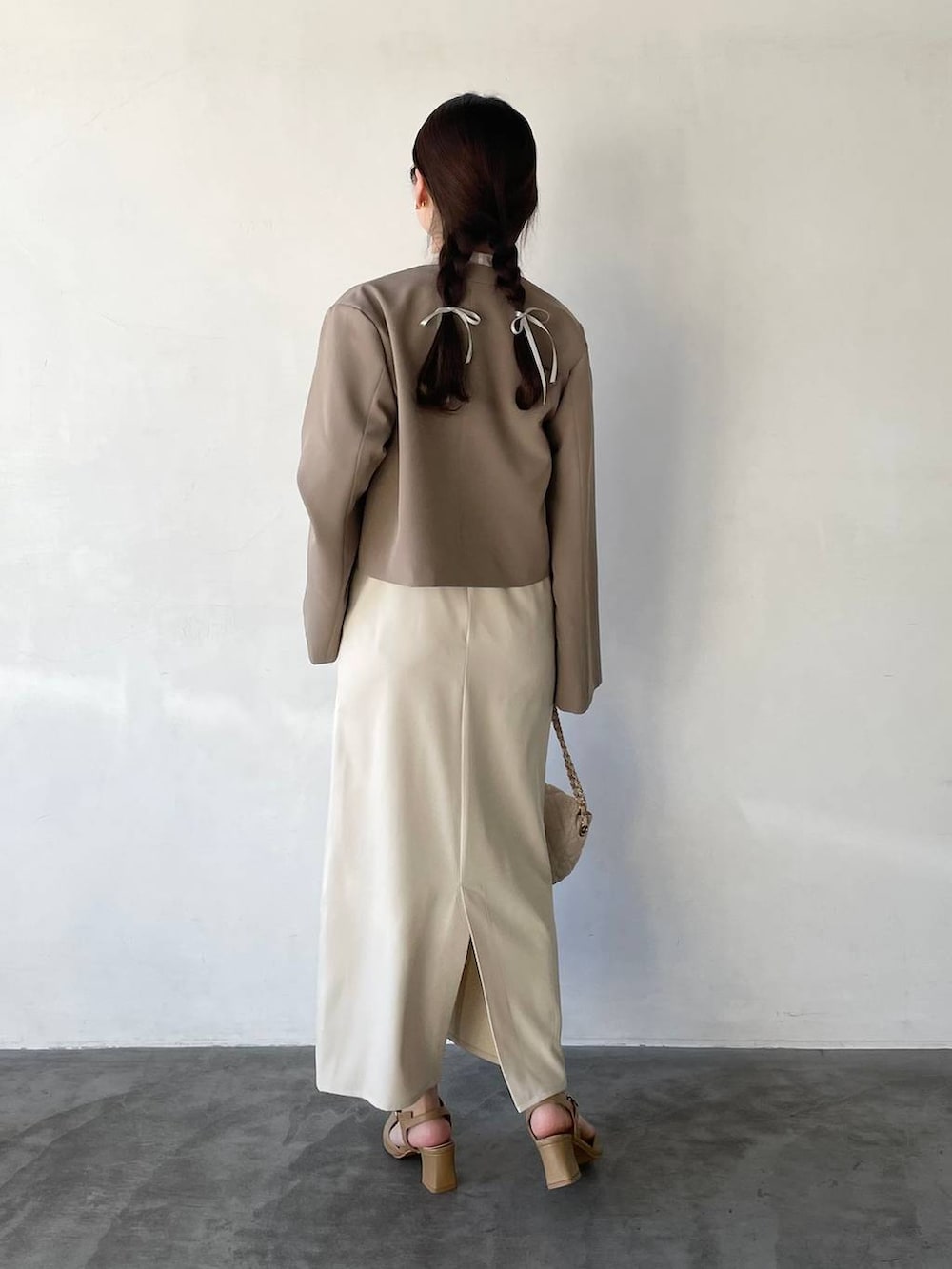 ホワイト系のドレス、ホワイト系のショルダーバッグ、ベージュ系のパンプスを着用したレディースの冬コーディネートの2枚目の写真