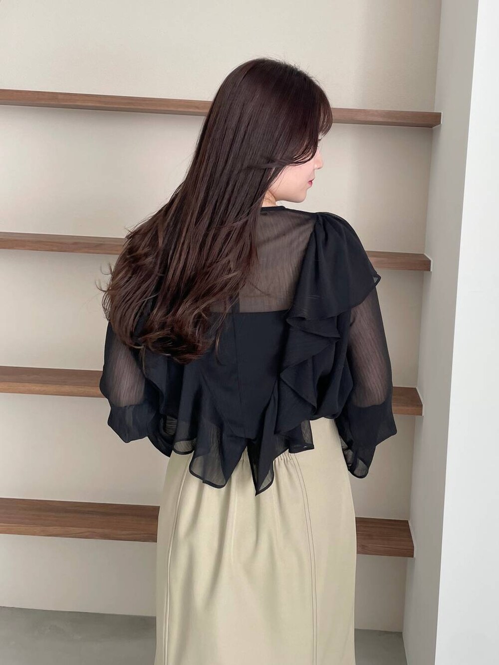 ブラック系のショルダーバッグ、ブラック系のパンプス、ベージュ系のスカートを着用したレディースの春コーディネートの4枚目の写真