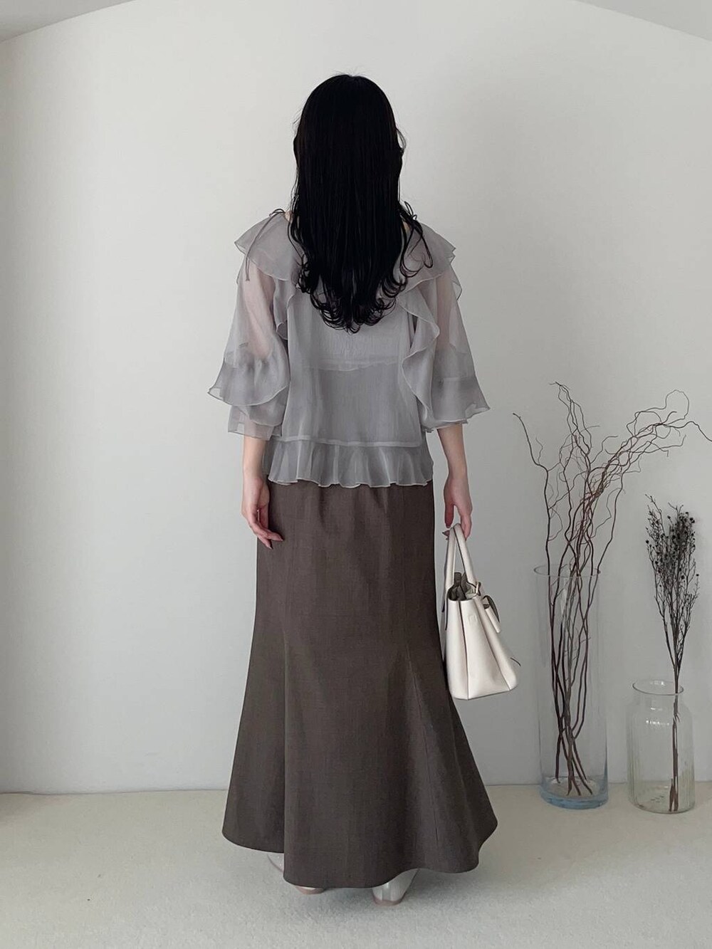 ホワイト系のショルダーバッグ、シルバー系のバレエシューズ、グレー系のスカートを着用したレディースの春コーディネートの2枚目の写真