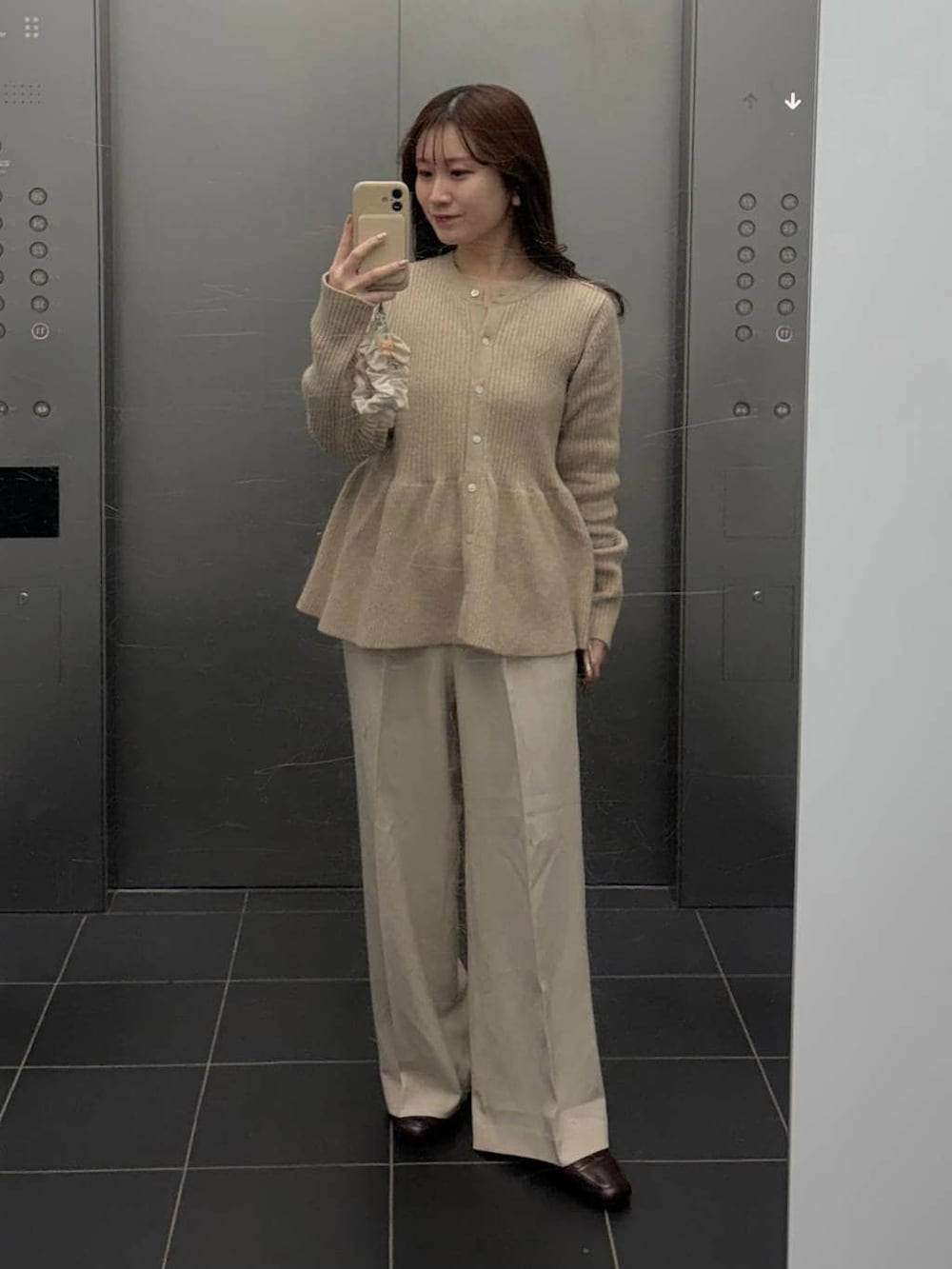 ブラウン系のボストンバッグ、ホワイト系のスラックス、ベージュ系のカーディガン/ボレロを着用したレディースの冬コーディネートの2枚目の写真