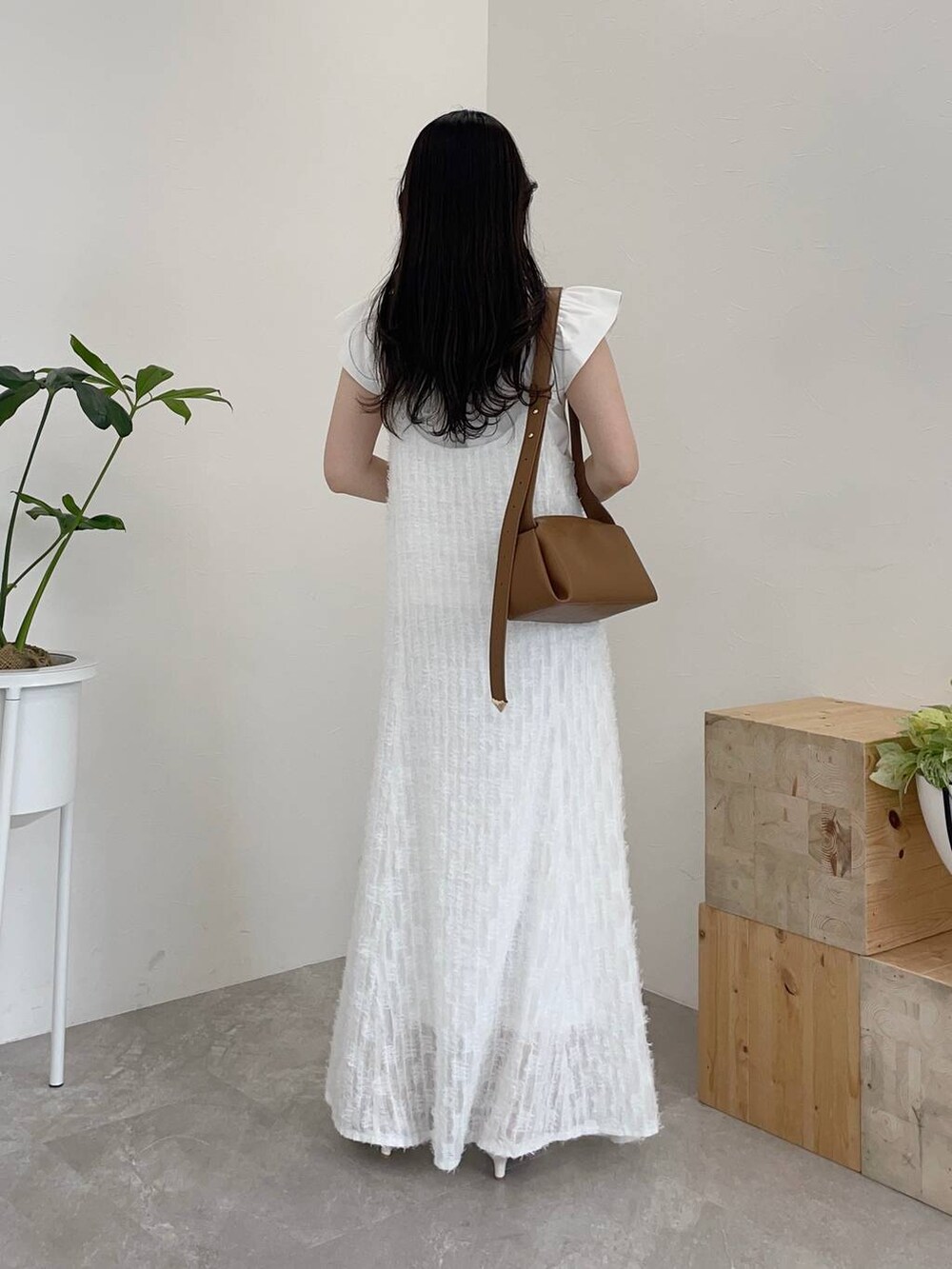 ホワイト系のワンピース、ホワイト系のTシャツ/カットソー、ブラウン系のショルダーバッグを着用したレディースの春コーディネートの2枚目の写真