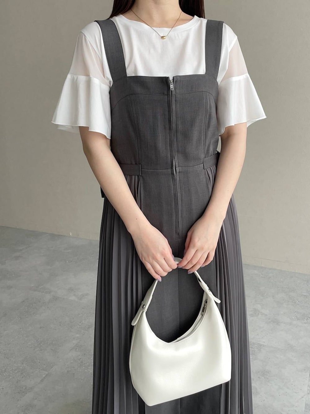 グレー系のジャンパースカート、ホワイト系のTシャツ/カットソー、ホワイト系のショルダーバッグを着用したレディースの春コーディネートの3枚目の写真