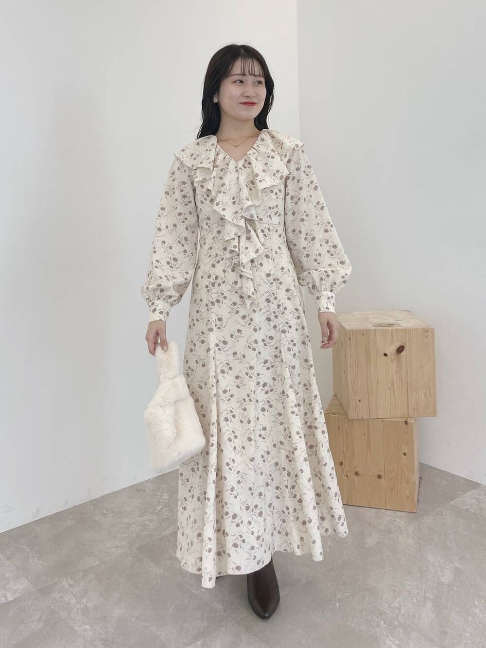 ブラウン系のカーディガン/ボレロ、ホワイト系のハンドバッグ、ブラウン系のブーツを着用したレディースの秋コーディネートの4枚目の写真