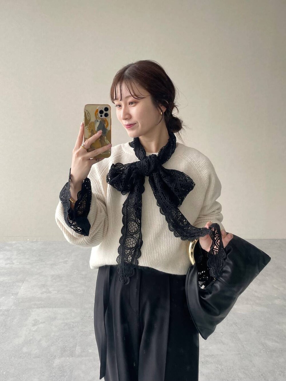 ホワイト系のニット/セーター、ブラック系のハンドバッグ、ブラック系のシャツ/ブラウスを着用したレディースの秋コーディネートの3枚目の写真