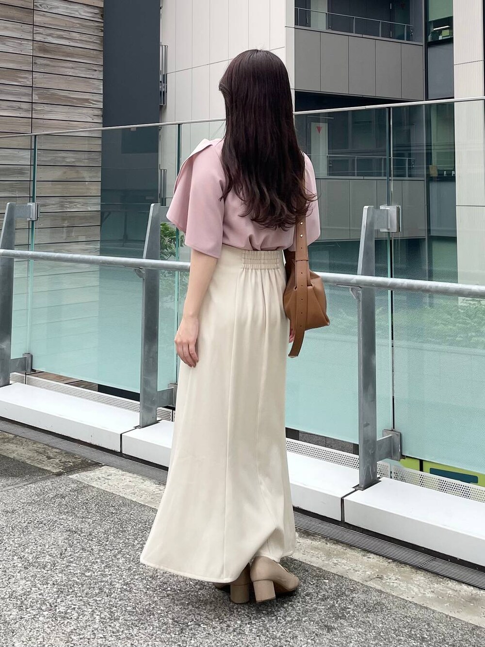 ブラウン系のショルダーバッグ、ベージュ系のスカート、ピンク系のTシャツ/カットソーを着用したレディースの夏コーディネートの2枚目の写真