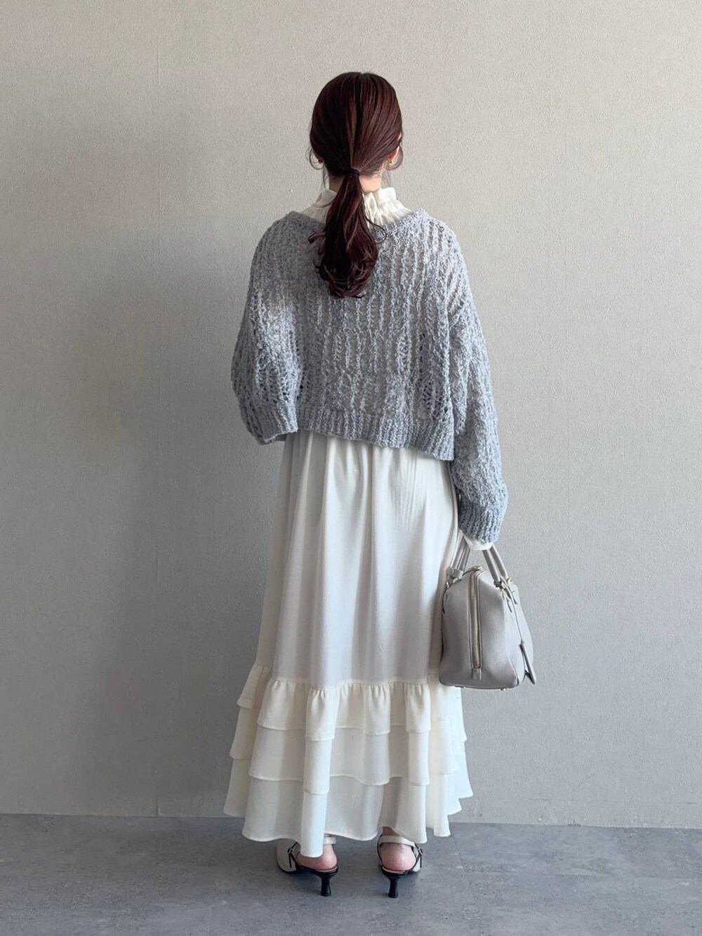 ベージュ系のハンドバッグ、ホワイト系のサンダル、ホワイト系のワンピースを着用したレディースの冬コーディネートの2枚目の写真