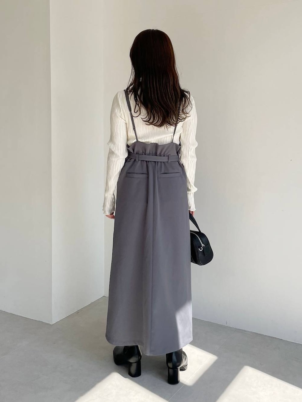 ブラック系のボストンバッグ、ブラック系のブーツ、グレー系のスカートを着用したレディースの秋コーディネートの7枚目の写真