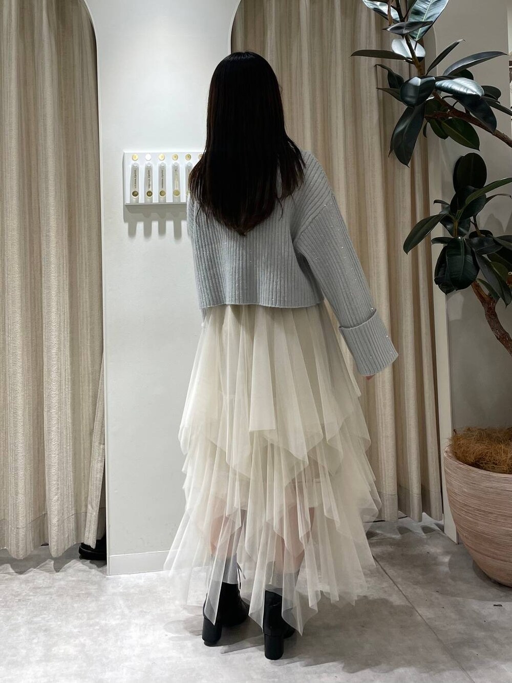 ブラック系のブーツ、ブルー系のニット/セーター、ホワイト系のスカートを着用したレディースの冬コーディネートの2枚目の写真