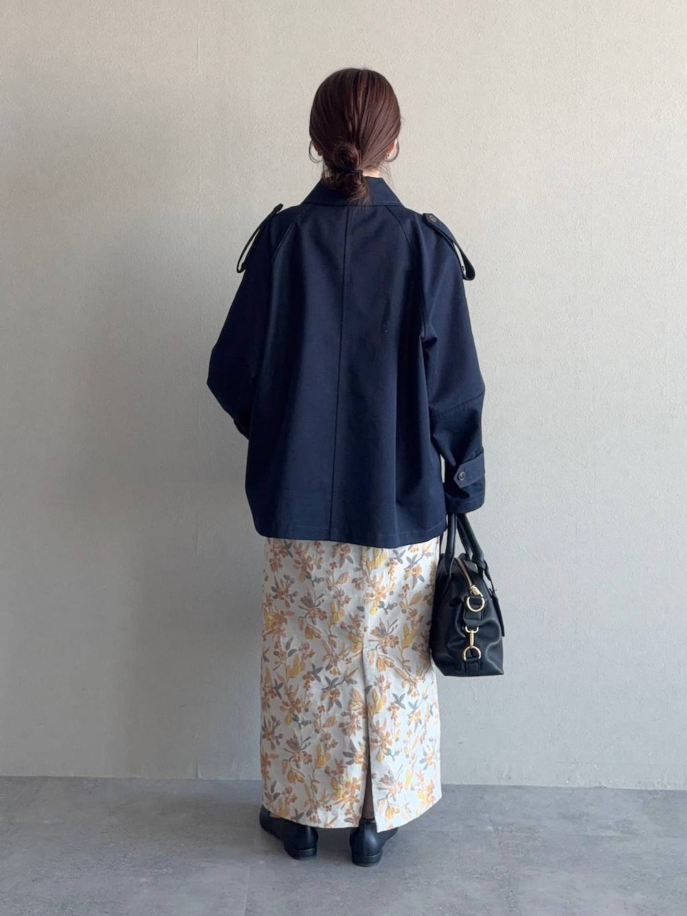 ブラック系のボストンバッグ、ホワイト系のスカート、ブラック系のパンプスを着用したレディースの冬コーディネートの2枚目の写真