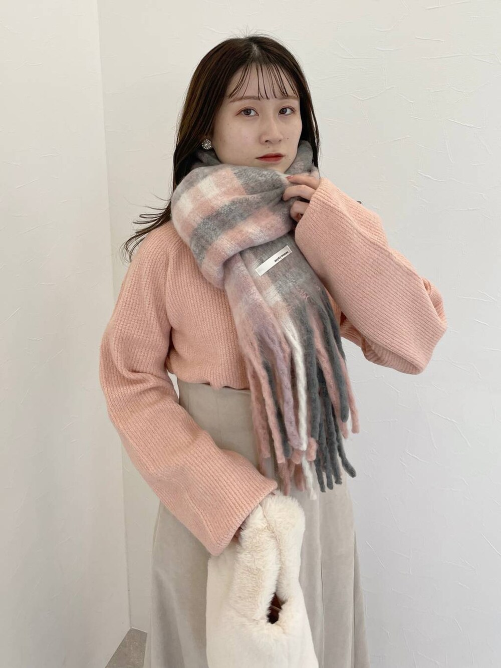 ピンク系のニット/セーター、グレー系のブーツ、ホワイト系のハンドバッグを着用したレディースの秋コーディネートの3枚目の写真