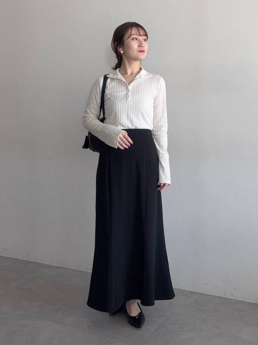 ブラック系のハンドバッグ、ベージュ系のテーラードジャケット、ブラック系のパンプスを着用したレディースの冬コーディネートの3枚目の写真