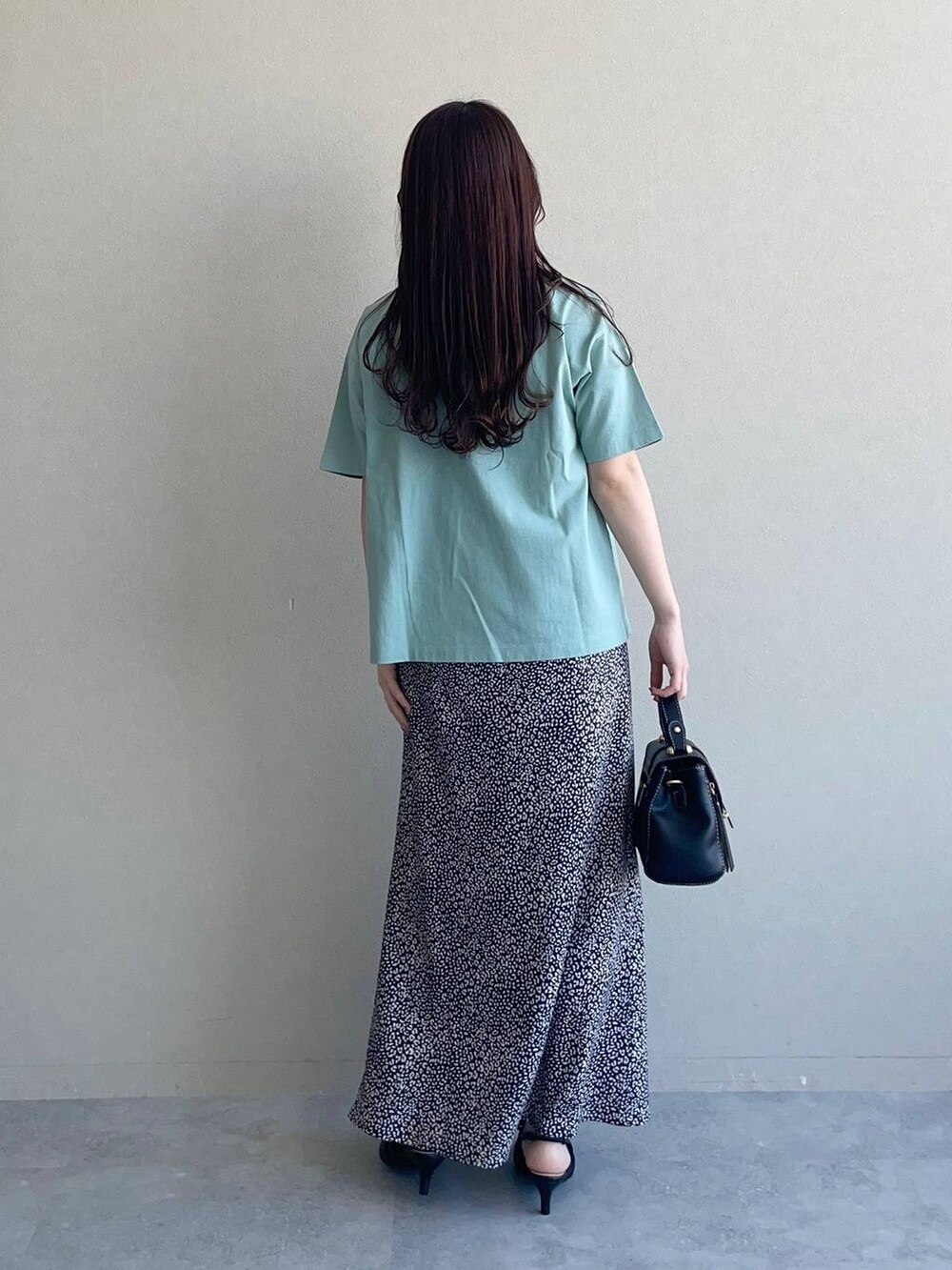 ブラック系のスカート、ブラック系のパンプス、グリーン系のTシャツ/カットソーを着用したレディースの春コーディネートの2枚目の写真