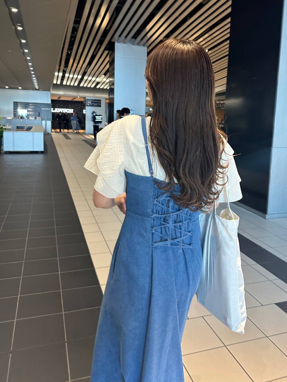 ブルー系のジャンパースカート、ホワイト系のサンダル、ホワイト系のTシャツ/カットソーを着用したレディースの夏コーディネートの5枚目の写真