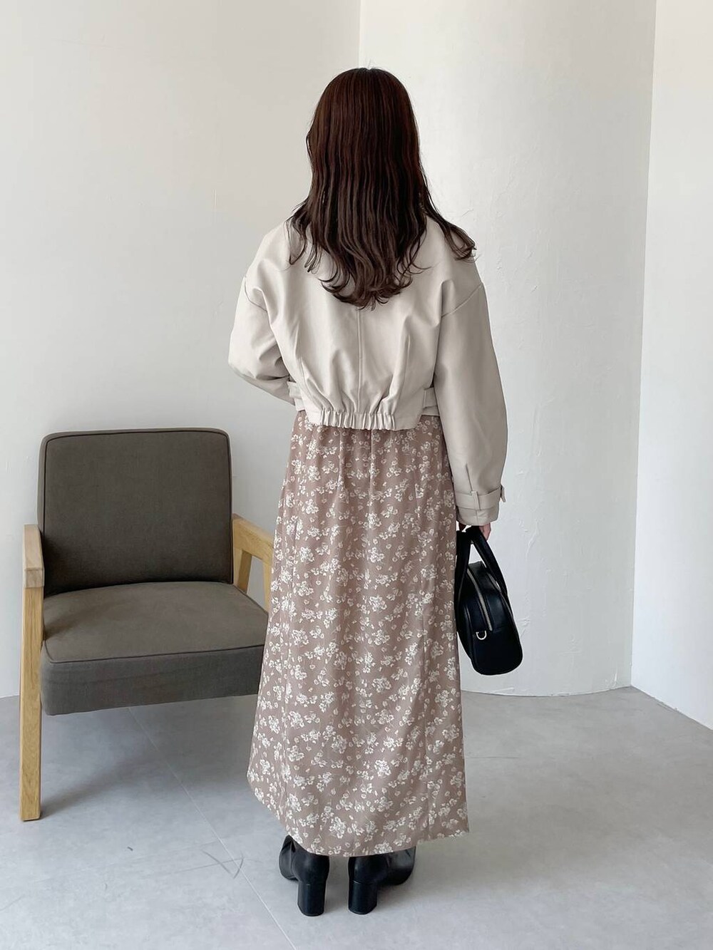 ブラック系のボストンバッグ、ブラック系のブーツ、ベージュ系のワンピースを着用したレディースの秋コーディネートの2枚目の写真