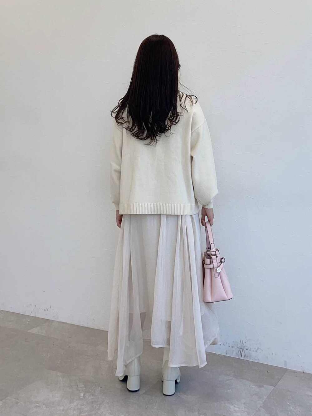ピンク系のショルダーバッグ、ホワイト系のブーツ、ホワイト系のスカートを着用したレディースの冬コーディネートの2枚目の写真