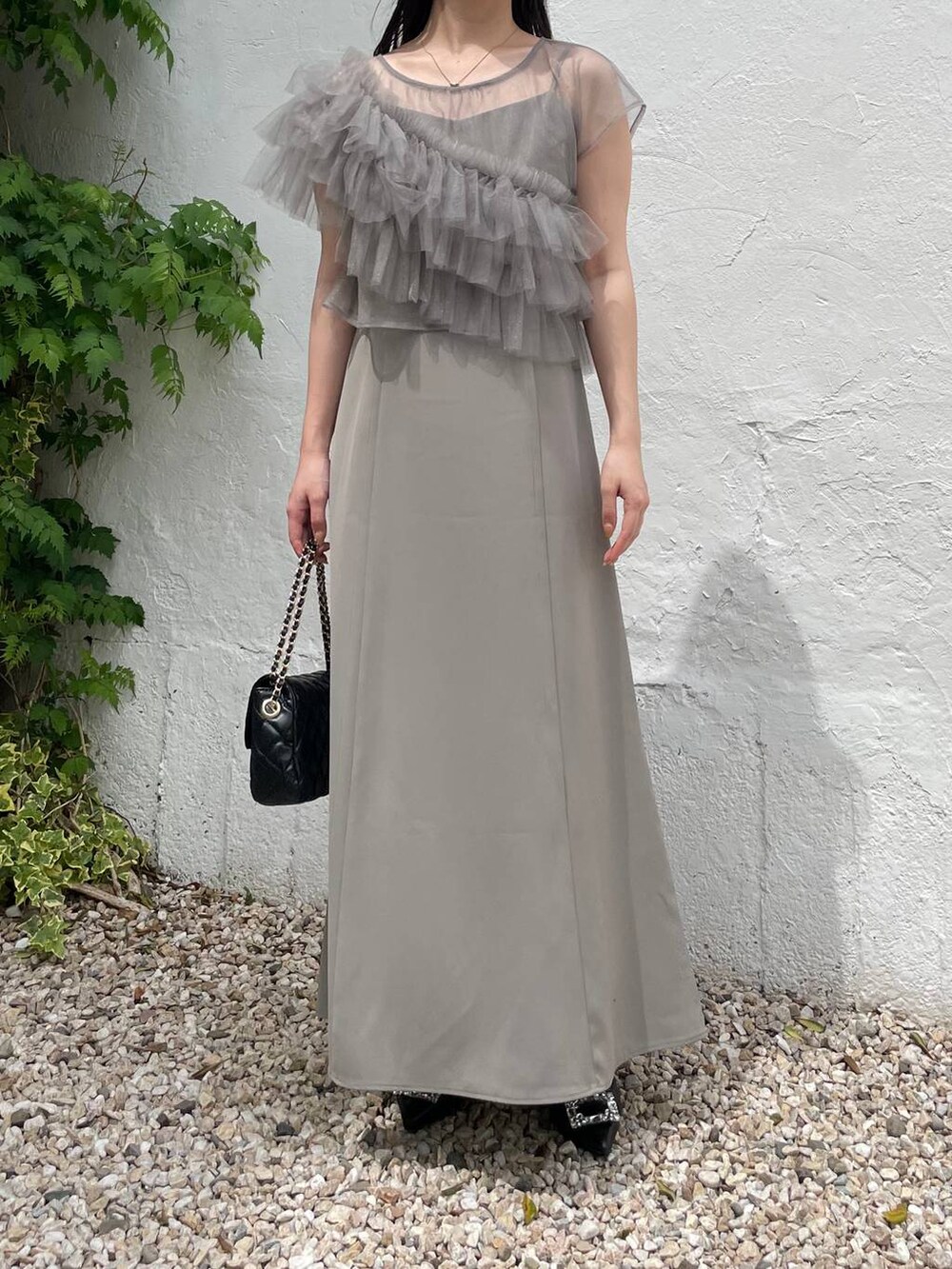 ブラック系のパンプス、グリーン系のドレス、ブラック系のショルダーバッグを着用したレディースの夏コーディネートの5枚目の写真